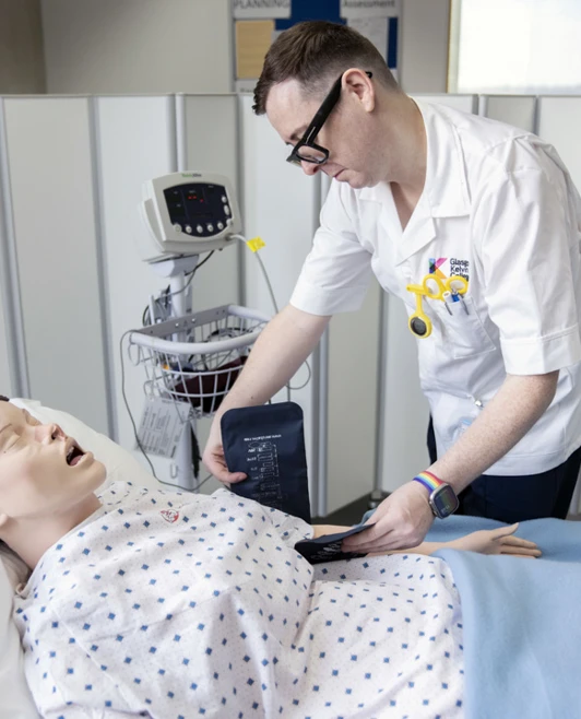 Student checks blood pressure on a medical training mannequin in a clinical skills lab Student checks blood pressure on a medical training mannequin in a clinical skills lab
